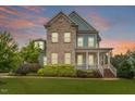 Inviting two-story home featuring a brick facade, covered porch, and lush landscaping against a colorful sky at 212 Preatonwood Dr, Apex, NC 27539