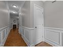 Hallway featuring hardwood floors, white trim, and access to other rooms, with a view of the living room fireplace at 238 Langford Valley Way, Cary, NC 27513