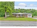 Traditional brick home featuring a covered front porch, lush lawn, and an attached garage at 3114 Alabama Ave, Durham, NC 27705