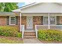 Close-up of brick home's front porch with white railings, steps and black shutters at 3114 Alabama Ave, Durham, NC 27705
