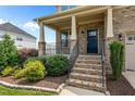 Inviting front porch with brick steps, columns, iron railings, and landscaped garden beds at 319 Brinkley Cir, Mebane, NC 27302