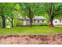 A cozy home nestled behind a classic brick wall, with mature trees framing the picturesque front yard at 504 Delaware Ave, Burlington, NC 27217