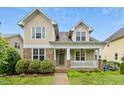 Inviting two-story home with a charming porch, stone accents, and lush landscaping at 59 Tobacco Farm Way, Chapel Hill, NC 27516