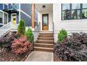 Inviting home entrance showcases wooden steps, lush shrubbery, and modern railing at 606 Velma Hopkins Ln, Raleigh, NC 27603