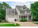 Attractive two-story home with a well-kept lawn, inviting porch, black shutters, dormer windows, and an attached garage at 1004 Manderston Ln, Apex, NC 27502