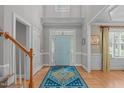 Welcoming foyer with hardwood floors, a patterned rug, a decorative front door, and a staircase at 1004 Manderston Ln, Apex, NC 27502
