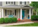 Inviting front porch with a turquoise bench, white columns, lovely landscaping, and a bright blue door at 1004 Manderston Ln, Apex, NC 27502