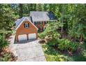 An aerial view of a beautiful brick home featuring a two-car garage surrounded by mature trees and a long driveway at 103 Lochwood West Dr, Cary, NC 27518