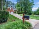 A brick home with black shutters, green lawn, mailbox and long driveway at 103 Lochwood West Dr, Cary, NC 27518