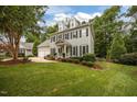 Traditional two-story home with light blue siding, dormer windows, green lawn, and lush landscaping at 106 Fawley Ct, Cary, NC 27519