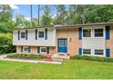 Charming split-level home featuring a brick facade, well-manicured lawn, and mature trees at 1109 Buckingham Rd, Garner, NC 27529
