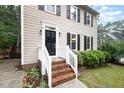 Charming front entrance with brick steps, white railings, a black front door and mature landscaping at 12 Striding Ridge Ct, Durham, NC 27713