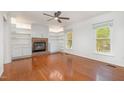 Bright living room featuring hardwood floors, a brick fireplace with built-in shelving, and abundant natural light at 12 Striding Ridge Ct, Durham, NC 27713