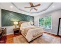 Serene bedroom with decorative wall, tray ceiling, hardwood floors, and natural light at 1216 Miracle Dr, Wake Forest, NC 27587