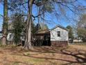 View of a spacious backyard with a deck, brick foundation, and mature trees at 1310 Ray Ave, Sanford, NC 27330