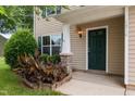 Close-up of a welcoming front porch with a green door, stylish column, and landscaped flower bed at 1310 Silver Dr, Mebane, NC 27302