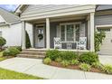 Inviting front porch featuring a cozy seating area, a lovely wreath, and well-maintained landscaping at 1374 Patriot Points Way, Fuquay Varina, NC 27526