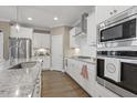 Modern kitchen featuring stainless steel appliances, granite countertops, and stylish white cabinetry at 1374 Patriot Points Way, Fuquay Varina, NC 27526
