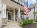 Inviting front porch with stone accents, a flag, and seating area at 146 Bent Willow Dr, Clayton, NC 27527