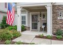 Inviting front porch featuring stone accents, a rocking chair, manicured landscaping, and decorative plants at 228 Ellisview Dr, Cary, NC 27519