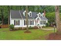 Charming home with dormer windows, a brick chimney, and manicured lawn with mature trees at 3016 Bolo Trl, Raleigh, NC 27615