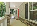 Covered front porch featuring stone accents, a red front door, and a view of the wooded surroundings at 305 Old School Rd, Chapel Hill, NC 27516