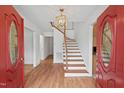 Bright foyer with hardwood floors, a wooden staircase, and a modern light fixture at 307 Country Club Dr, Durham, NC 27712