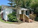 Exterior side view of the house, featuring siding, windows, and wooden porch with railing at 3810 Pendergrass St, Durham, NC 27704