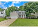Two-story home featuring a well-manicured lawn and two-car garage, with a welcoming front porch showcasing classic columns at 4028 Winecott Dr, Apex, NC 27502