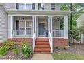 Inviting front porch with brick base, classic white columns, and fresh landscaping, creating a welcoming entrance at 4028 Winecott Dr, Apex, NC 27502