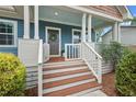 The inviting front porch has wood stairs, white railings, blue walls and a swing at 415 Dupree St, Durham, NC 27707