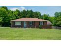 Classic brick home with a neatly kept lawn, shaded by mature trees in a serene setting at 424 Camp Rd, Burlington, NC 27217