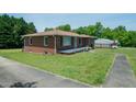Well-kept brick home featuring a quaint front porch and a lush green lawn at 424 Camp Rd, Burlington, NC 27217