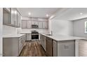 Open kitchen boasts gray cabinets, stainless steel appliances, and a large center island with quartz countertops at 510 Resteasy Dr, Apex, NC 27539