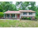 Traditional two-story home with a welcoming front porch, black shutters and a red front door surrounded by a lush lawn at 5121 Raintree Rd, Durham, NC 27712