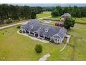 Aerial view of gray home with large covered front porch, barn, pool, and fenced yard with landscaping at 5200 Pulley Town Rd, Zebulon, NC 27597