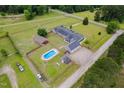 Aerial view of home, barn and pool on large grassy lot with perimeter fencing, outbuildings and landscaping at 5200 Pulley Town Rd, Zebulon, NC 27597
