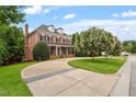 Stately brick home with a well-manicured lawn, mature trees, and an in-ground pool at 6217 Battleford Dr, Raleigh, NC 27612