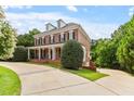 Elegant brick home with a circular driveway, manicured landscaping, and a classic architectural design at 6217 Battleford Dr, Raleigh, NC 27612