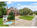 Stately brick home with a well-manicured lawn, mature trees, and an in-ground pool at 6217 Battleford Dr, Raleigh, NC 27612