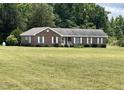 Expansive lawn surrounds this brick house with white shutters, offering curb appeal at 65 Opie Frazier Rd, Henderson, NC 27537