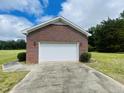 Detached brick garage with a pristine white door and a well-maintained driveway at 65 Opie Frazier Rd, Henderson, NC 27537