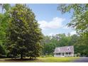 Scenic view of a home exterior enveloped by mature trees and a verdant lawn under a blue sky at 657 Lakeview Dr, Stem, NC 27581