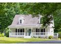 Exterior home view features a covered porch and inviting curb appeal surrounded by lush trees at 657 Lakeview Dr, Stem, NC 27581