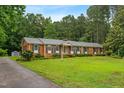 Traditional brick home with a long driveway and a lush green lawn surrounded by mature trees at 6909 Hickory Dr, Raleigh, NC 27603