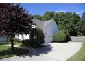 Long driveway leads to a home with a side-entry garage surrounded by mature trees and lush landscaping at 70 Glen Oaks Drive Dr, Youngsville, NC 27596