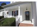 Close up of a charming covered porch with flowers, white columns and a decorative front door at 70 Glen Oaks Drive Dr, Youngsville, NC 27596
