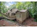 Exterior view of multi-level home with wooden walkways and siding, nestled in a wooded area with mature trees at 73 Stoneridge Rd, Durham, NC 27705
