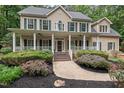 Classic two-story home showcasing a welcoming covered porch and established landscaping at 7811 Still Crossing Rd, Chapel Hill, NC 27516
