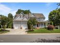 Two story home featuring a three car garage, mature trees, nice landscaping and inviting front porch at 100 Maywood Way, Chapel Hill, NC 27516
